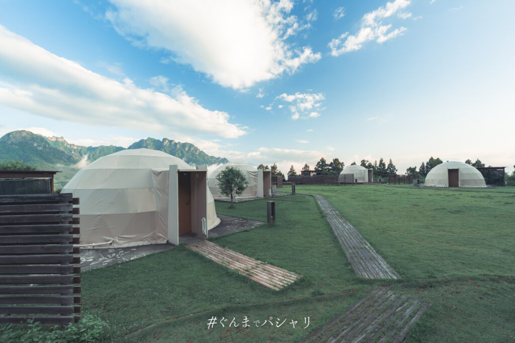 芝生に並ぶドームテントと遠くの妙義山を広角で撮影