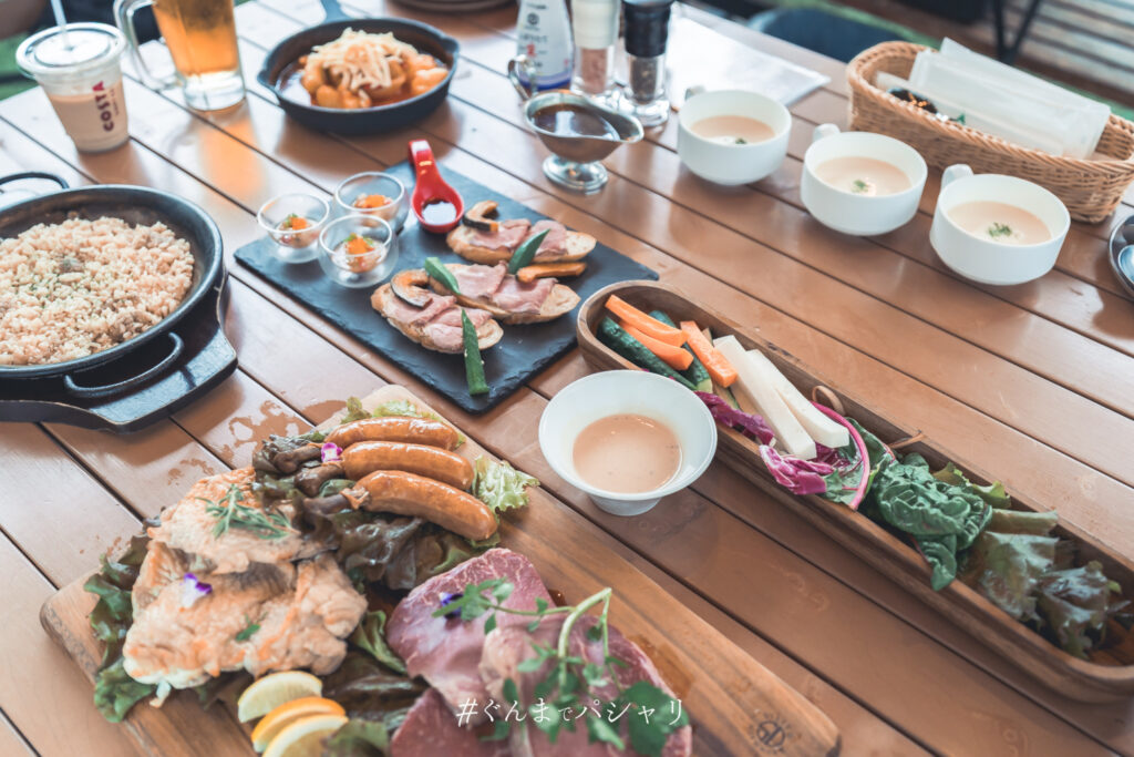 BBQの夕食。赤城鶏のもも肉、ソーセージ、牛肉、野菜スティック、スープが並ぶテーブル